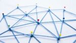 Blaue Fäden sind zwischen Stecknadeln zu einem Netz gespannt