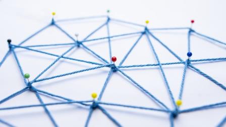 Blaue Fäden sind zwischen Stecknadeln zu einem Netz gespannt